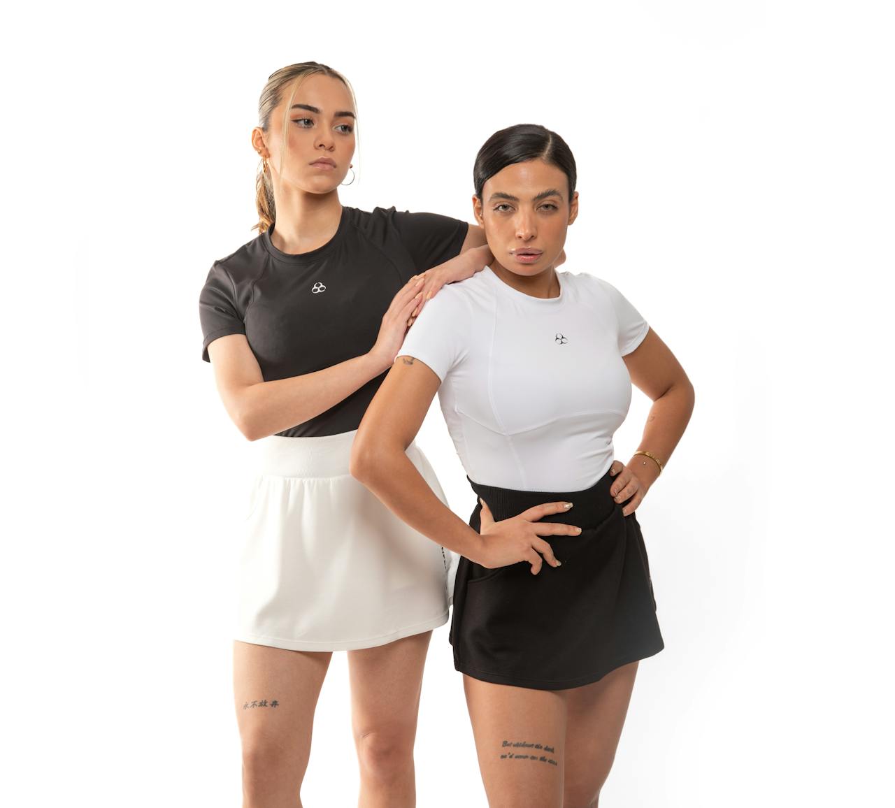 Two women in stylish sportswear posing during a studio photoshoot, showcasing athletic fashion.
